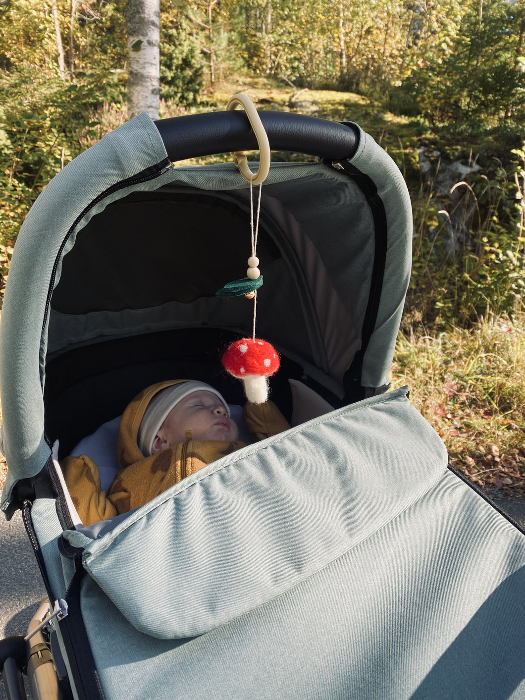 Handgjord barnvagnsleksak med motiv av en röd flugsvamp – ekologisk mobil för baby i skogsinspirerat tema för härliga promenader