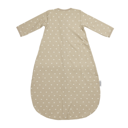 Närbild på beige sovpåsemed vita små hjärtan som håller barnet varmt och tryggt hela natten