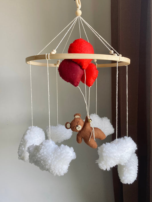 Ekologisk babyleksak som inredning till barnrum eller ditt sovrum. Häng den där bebisen sover. Med motiv av vita moln och  en björn som flyger med tre röda ballonger av filt. Handgjort och lokalt tillverkad leksak