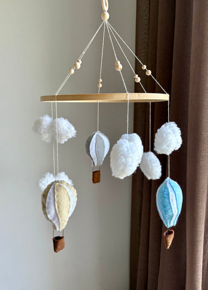 Babymobil i filt, luftballonger i blått, grått och beige – babyinredning