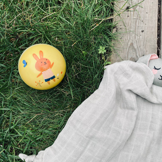 Gul badboll för barn ligger i ett grönt gräs – Sweety Ball för lek på stranden eller i poolen. 