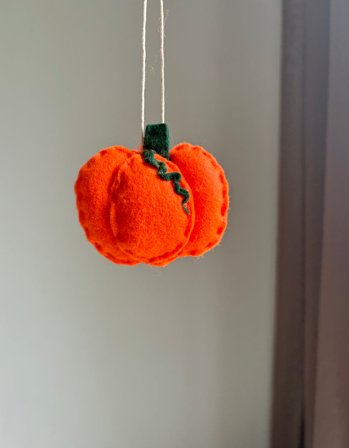 Handgjort barnvagnshänge i filt formad som orange pumpa